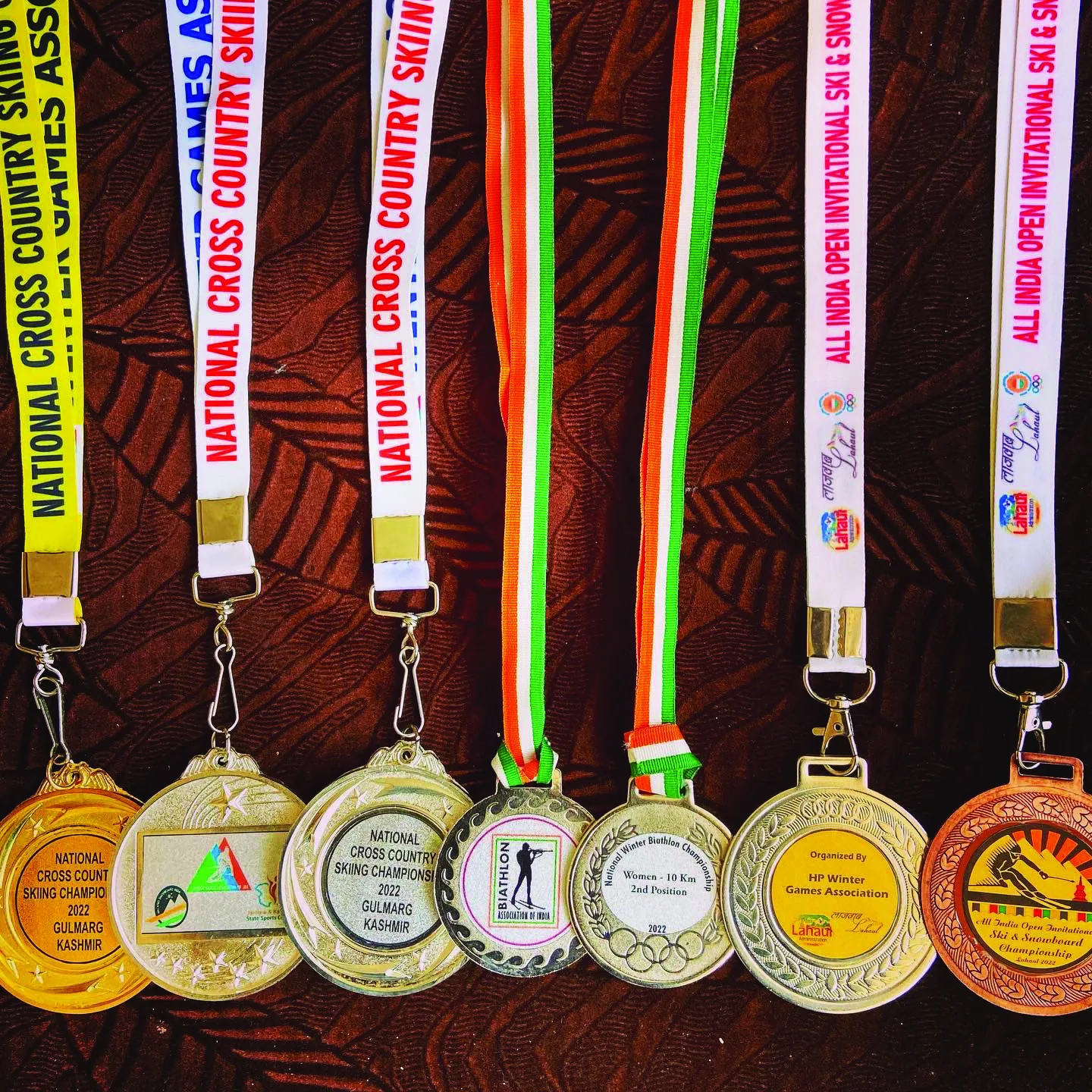 Six skiing medals hanging side by side on printed lanyards reading National Cross Country Skiing.