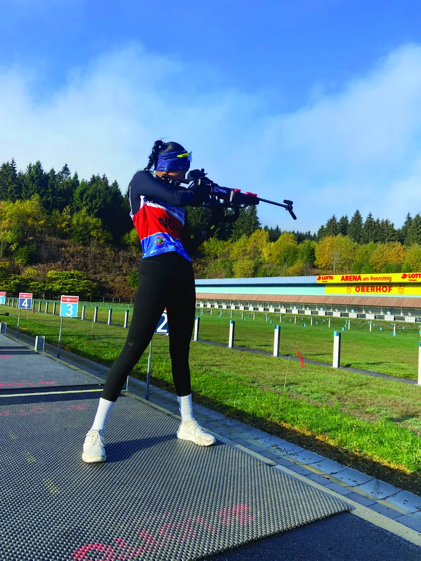Bhavani training on roller skis along a tarmac road beside an autumn field, poles planted mid-push.